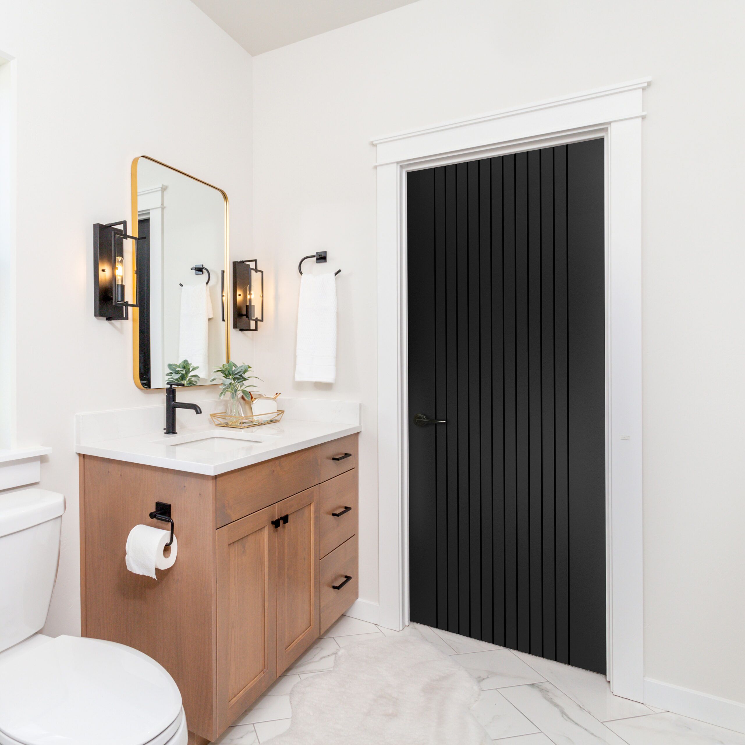 A modern farmhouse bathroom with wood cabinets, quartz counterto